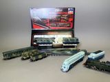 Plusieurs petits trains sont alignés sur une table, à côté d'une boîte