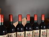 six bottles of red wine are lined up on a table