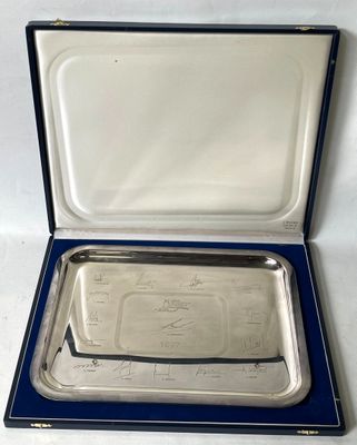 une assiette en argent dans un étui bleu posé sur une surface blanche