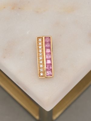 un gros plan d'une bague sertie d'un diamant rose et blanc posée sur une table en marbre