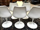 four white tulip chairs sitting on top of a rug in a room