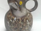 un vase marron sur lequel est collé un autocollant jaune