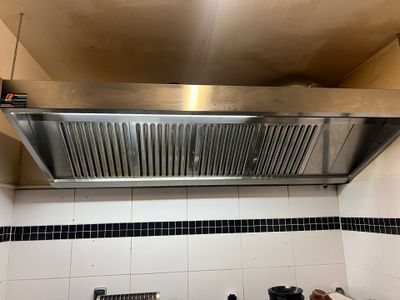 a stainless steel range hood in a kitchen with black and white tiles