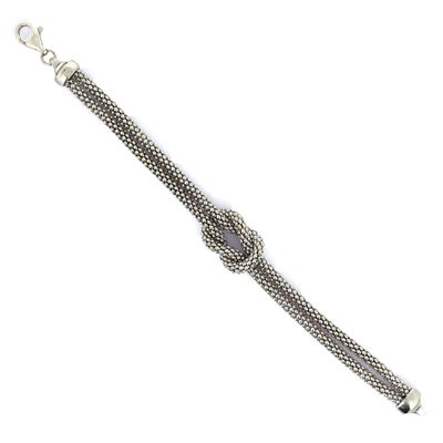 a close up of a silver bracelet with a knot on it