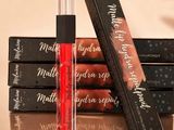 three lip glosses are sitting on top of a stack of books