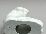 a white ceramic sculpture of a dog with a hole in it ' s mouth