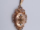 a close up of a gold pendant with a blue stone in the center