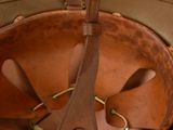 a brown leather hat with a leather strap hanging from it ' s side