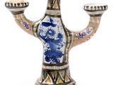 a blue and white vase with two candles on it
