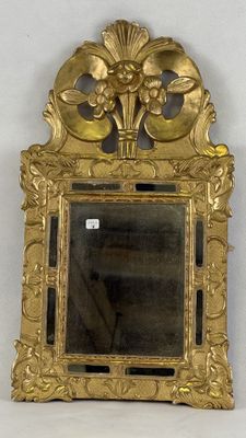 miroir avec un cadre doré et un motif floral sur le devant