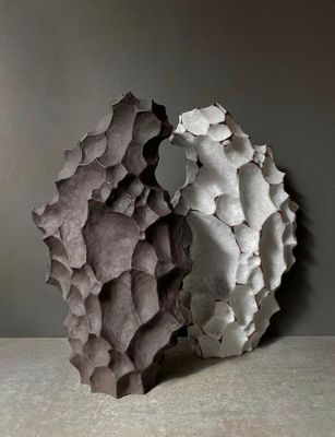 des sculptures en béton sont posées sur une table devant un mur gris