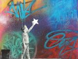 tableau représentant un jeune garçon tenant un avion en papier devant un mur recouvert de graffitis