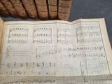 a book with music notes on it sitting next to a stack of old books