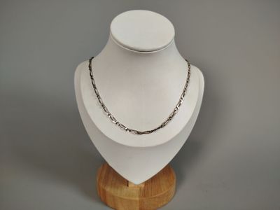 silver chain necklace on a wooden stand on a gray background