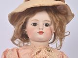 a doll that is wearing a pink dress and a hat