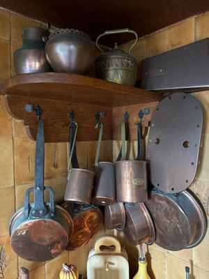 de nombreuses casseroles et poêles accrochées au mur de la cuisine