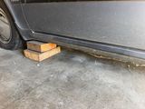 a car that is parked in a garage with a wooden block on the ground