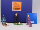 three figurines of people standing in front of a blue box