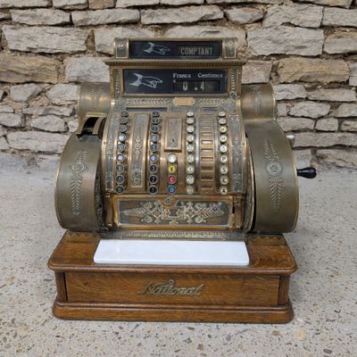 an old fashioned cash register sitting on top of a wooden stand