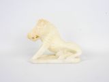 une figurine en ivoire représentant un lion assis sur ses pattes arrière