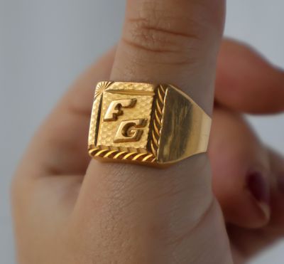 une personne tenant une bague en or sur laquelle est gravé un numéro