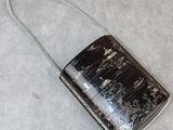 un sac à main noir avec une poignée argentée sur un fond gris