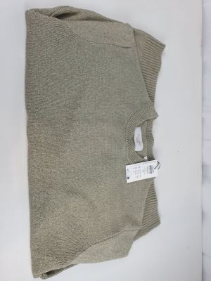 a close up of a sweater on a table with a tag on it