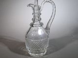 a clear glass vase with a handle on a table