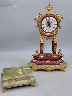 une petite horloge posée sur une table à côté d'une petite boîte