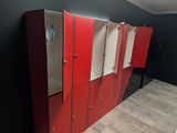 a row of red lockers in a room with a skylight