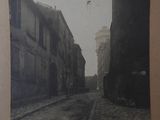 an old photo of a narrow street with buildings and a bird flying in the sky