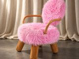une chaise rose avec une structure en bois et une assise recouverte de fourrure rose