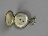 an antique silver pocket watch with a key on a table