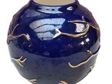 a blue vase with a gold leaf design on it