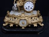 a gold clock with a statue on top of it