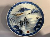 une assiette bleue et blanche sur laquelle figurent des personnes à bord d'un bateau