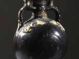 un vase noir orné d'un motif doré sur le dessus