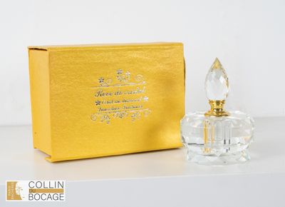un petit flacon de parfum en verre posé à côté d'un coffret doré