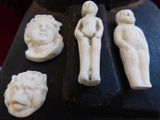 four figurines sitting on a table next to a vase