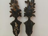 two metal vases with flowers on them sitting on a table