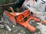 une déneigeuse orange posée par terre à côté d'un tas d'ordures