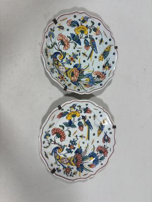 two plates with floral designs on them sitting on a table