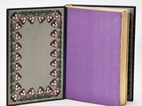 an open book with a purple cover sitting on top of a white table