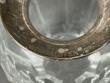 a glass vase with a metal lid on a table
