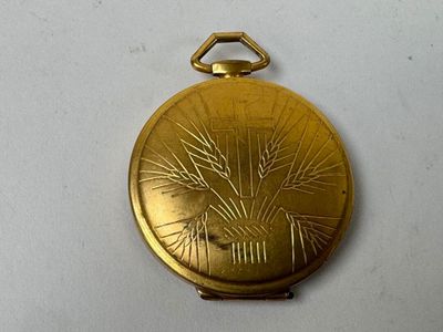 a gold pocket watch with a tree design on it
