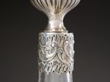 an old silver and glass bottle with a decorative design on the top