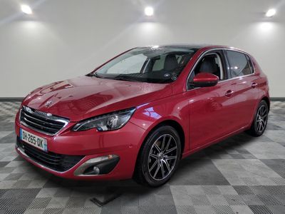 une voiture rouge est garée dans une pièce au sol en damier