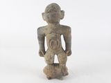 une vieille figurine représentant un homme debout sur une surface blanche