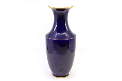 un vase bleu à bord doré posé sur une surface blanche