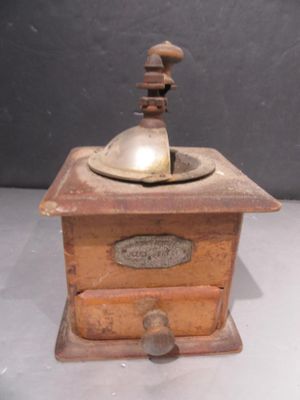 a small wooden grinder with a bell on top of it